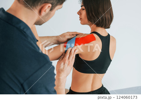 On the left hand. Woman visiting physiologist that putting kinesio tape on the skin On the left hand. Woman visiting physiologist that putting kinesio tape on the skin 124060173