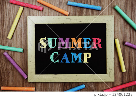 Summer Camp text on blackboard with chalk stick various colors on wooden background Summer Camp text on blackboard with chalk stick various colors on wooden background 124061225