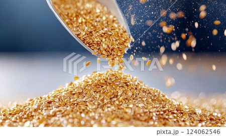 Golden flax seeds pouring from spoon onto pile in close-up shot. 124062546