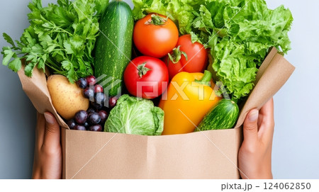 Fresh vegetables and fruits in a paper bag held by hands. 124062850