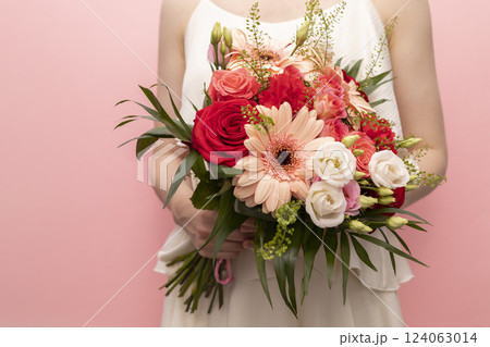 Cropped Woman Holds Beautiful Fresh Bouquet Of Flowers For Wedding Or Occasion On Pink Background. Colorful Mixed Roses, Carnation Shabot, Green Leaves, Gerber. Horizontal Plane 124063014