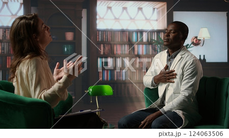 Psychiatrist in a serious conversation with a medic practitioner, listening to medical career difficulties and mental health struggles. Powerless doctor discussing about PTSD in therapy. Camera A. 124063506