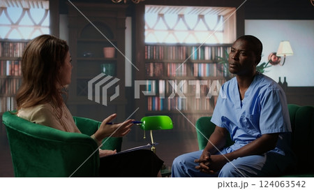 African american male nurse experiences derealization in a counseling session, dealing with post traumatic stress disorder. Medical assistant in therapy struggles with his emotions. Camera A. 124063542