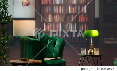 Stylish refined library lounge space featuring vintage decor and warm lighting, whiskey glasses on a table evoking the upscale atmosphere of old money. Success and aristocracy partnerships. Stylish refined library lounge space featuring vintage decor and warm lighting, whiskey glasses on a table evoking the upscale atmosphere of old money. Success and aristocracy partnerships. 124063657