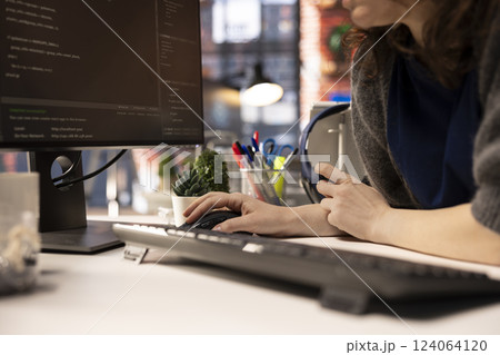 Female developer coding cloud computing applications on pc in a modern tech workspace. Woman IT specialist focuses on the software development process for productivity and innovation. 124064120