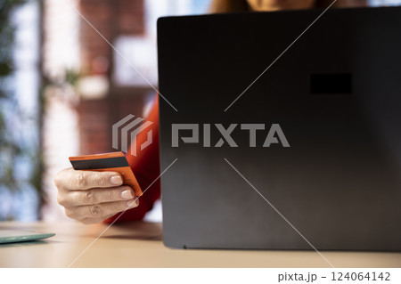 Casual woman at home entering her card digits to renew an account subscription, managing the services on her laptop. Person transferring money on the internet, updating the credentials. 124064142