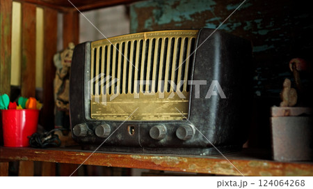An antique radio with analog controls sits on a wooden shelf An antique radio with analog controls sits on a wooden shelf 124064268