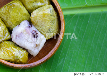 Bundled boiled sticky rice with banana and black beans wrapped in banana leaves 124064893