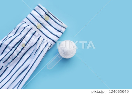 Detergent powder in measuring spoon with shirt before washing. Laundry concept. Detergent powder in measuring spoon with shirt before washing. Laundry concept. 124065049