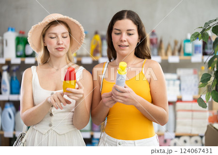 Young female friends choosing mosquito repellent in store Young female friends choosing mosquito repellent in store 124067431