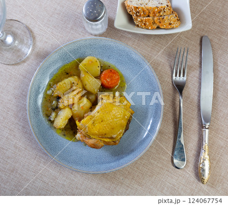 Baked chicken thigh served with stewed potatoes 124067754