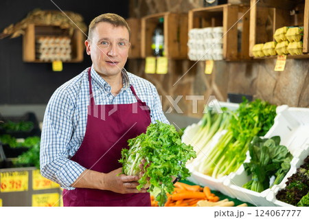 Male employee was distracted for minute and stands smiling with crisp lettuce in hands 124067777