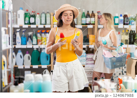 Woman choosing mosquito spray in supermarket in front of shoppers 124067988
