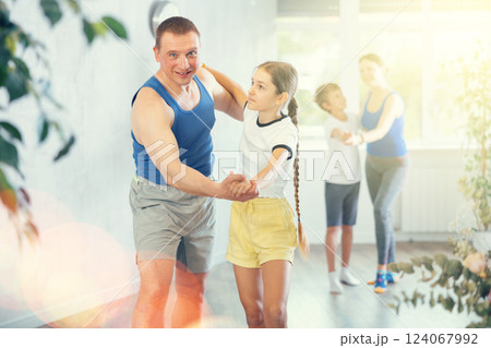 Active school girl practicing dance in pair with her sporty middle-aged father in dance hall during family training 124067992
