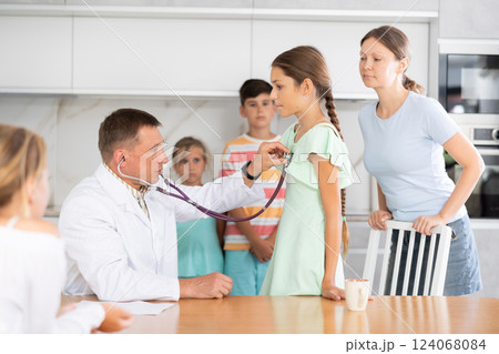 Family doctor writes down complaints of the children of large family and writes out prescription Family doctor writes down complaints of the children of large family and writes out prescription 124068084