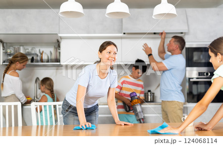 Friendly large family cleans room together. Mom and daughter are dusting table. Son is vacuuming oom. Father together with daughters wipe dust Friendly large family cleans room together. Mom and daughter are dusting table. Son is vacuuming oom. Father together with daughters wipe dust 124068114