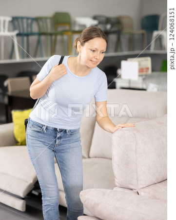 Woman in store inspects upholstered furniture. 124068151