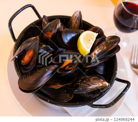 Steamed tasty mussels served on pan with lemon, spanish tapas Steamed tasty mussels served on pan with lemon, spanish tapas 124068244