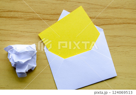 Top view of empty yellow notepad inside an envelope with crumpled paper with customizable space for text. 124069513