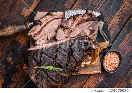 Slow ccoked sliced Venison leg, roasted game meat of deer on a board with herbs. wooden background. top view Slow ccoked sliced Venison leg, roasted game meat of deer on a board with herbs. wooden background. top view 124070026