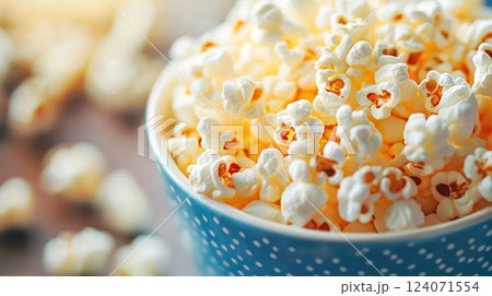 Delicious freshly popped popcorn in a blue bowl with a scattering of kernels 124071554