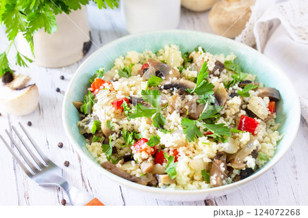 Healthy diet food. Vegan salad close-up with couscous and champignons on a wooden kitchen table. 124072268
