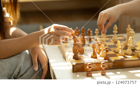 Close up shot of two players playing chess in a sunlit room 124073757