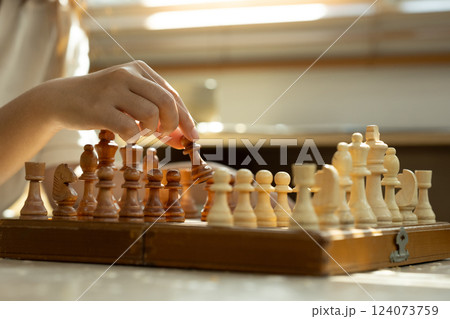 Hand moving a chess piece on wooden board. Strategy, decision making and board games concept Hand moving a chess piece on wooden board. Strategy, decision making and board games concept 124073759