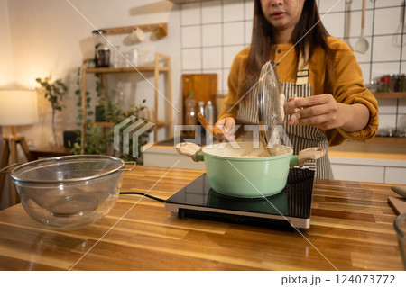Young woman in an apron cooking a simple meal in her home kitchen 124073772
