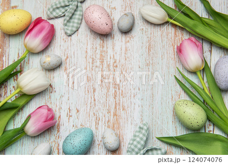 Easter eggs and tulips creating a frame on wooden background Easter eggs and tulips creating a frame on wooden background 124074076