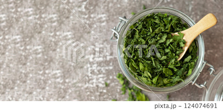 Glass jar with green dry parsley. Vegetarian bio organic salad herb healthy eating. Home garden immunity-boosting herbs. Seasonal harvest Glass jar with green dry parsley. Vegetarian bio organic salad herb healthy eating. Home garden immunity-boosting herbs. Seasonal harvest 124074691