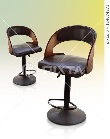 ancient and old two brown stools with backrest, old metal legs, brown color leather seat on gradient white and yellowand green background, object, comfortable, decor, copy space 124074871