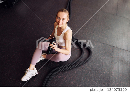 Top view. Sitting and taking a break. Young beautiful woman in sportive clothes have fitness day in the gym 124075390