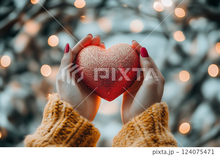 Red Heart Held in Hands with Sparkling Light Against a Soft Background 124075471