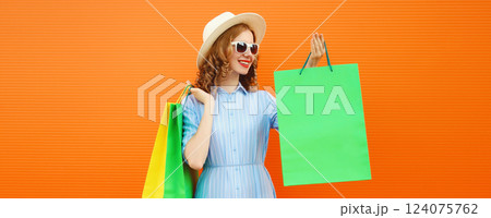 Stylish beautiful happy woman with colorful shopping bags in summer hat on orange Stylish beautiful happy woman with colorful shopping bags in summer hat on orange 124075762