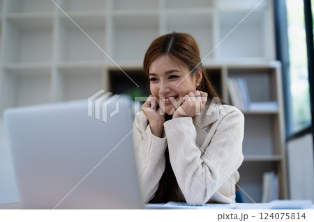 Confident business woman smiling Show successful gestures at her desk with market charts and documents in office Confident business woman smiling Show successful gestures at her desk with market charts and documents in office 124075814