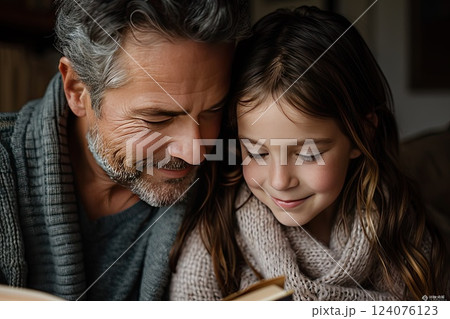 Grandfather and granddaughter share a cozy reading moment in a warm living room on a quiet afternoon Grandfather and granddaughter share a cozy reading moment in a warm living room on a quiet afternoon 124076123