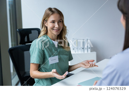 Female doctor wearing uniform talking to patient during consultation 124076329