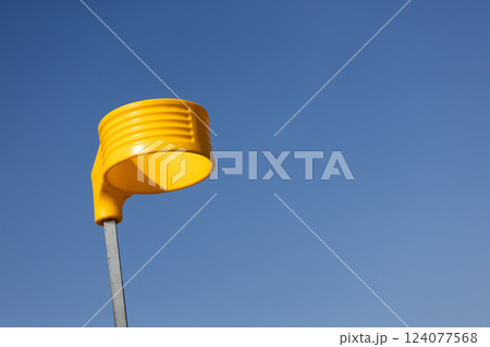 A Bright and Cheerful Yellow Object Stands Out Against a Clear Blue Sky, Showcasing a Unique Design That Captures the Eye with Its Vibrant Color and Distinct Shape 124077568
