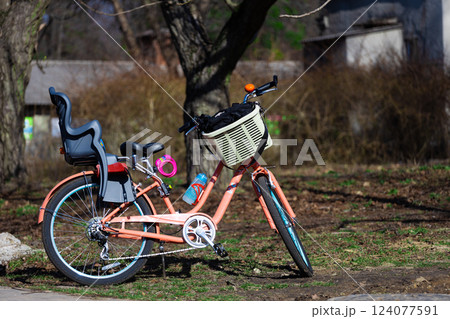 Charming Pink Bicycle with Child Seat and Basket Nestled Among Nature's Beauty on a Sunny Day in the Park Charming Pink Bicycle with Child Seat and Basket Nestled Among Nature's Beauty on a Sunny Day in the Park 124077591