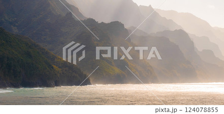 The Napali Coast on Kauai Island, Hawaii, features rugged cliffs, lush greenery, and jagged peaks descending into the ocean under soft sunlight. The Napali Coast on Kauai Island, Hawaii, features rugged cliffs, lush greenery, and jagged peaks descending into the ocean under soft sunlight. 124078855
