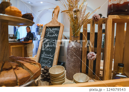 A luxury hotel interior features a chalkboard menu, rustic decor, and baked goods. A staff member is present, enhancing the welcoming atmosphere. A luxury hotel interior features a chalkboard menu, rustic decor, and baked goods. A staff member is present, enhancing the welcoming atmosphere. 124079543