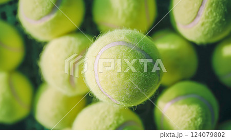 Bright yellow tennis balls stacked together in a sports equipment container 124079802