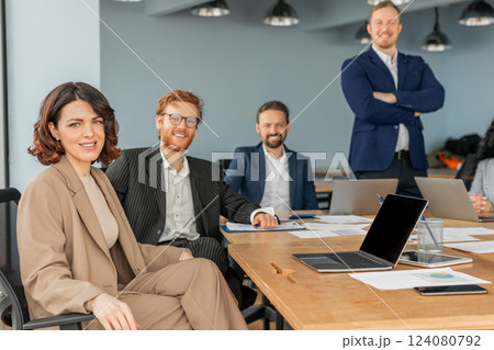 A diverse team of four professionals sits around a conference table in a modern office space. They appear to be in the midst of a successful business meeting. 124080792