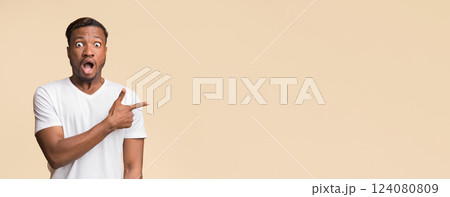 Look There. Surprised Black Man Pointing Finger Aside Standing In Studio Over Yellow Background. Free Space For Text 124080809