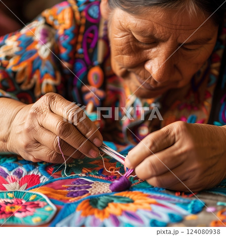 A traditional Mexican embroiderer brings vibrant Otomi patterns to life with meticulous, colorful stitches. 124080938