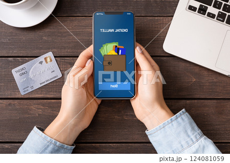 Mobile banking. Woman holding smartphone with digital wallet application. credit card on table, top view 124081059