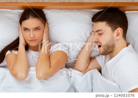 Snorting Problem. Angry Wife Covering Ears Trying To Sleep Near Snoring Husband In Bed At Home. Selective Focus, Top View 124081076