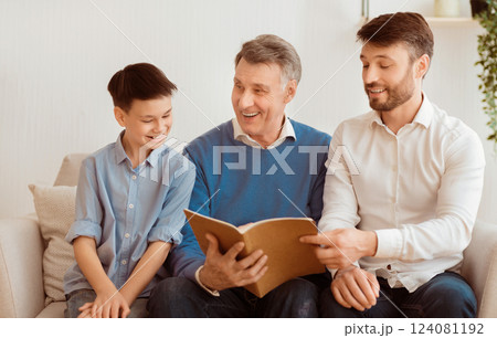 Little Boy, His Dad And Grandpa Reading Book Sitting On Sofa At Home. Weekend With Father And Grandfather. Selective Focus 124081192