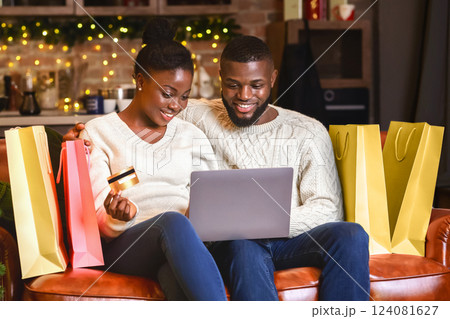 Seasonal sales. Happy african american couple buying Christmas presents online, using laptop and credit card. Seasonal sales. Happy african american couple buying Christmas presents online, using laptop and credit card. 124081627
